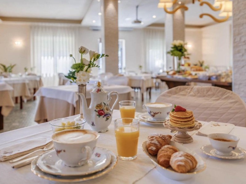 Tavola imbandita con cappuccino, cornetti e spremuta