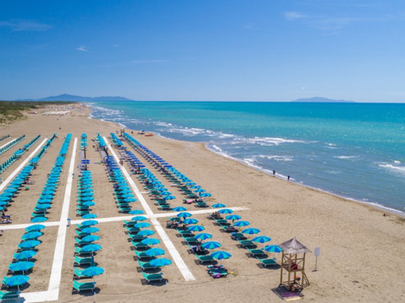 File di ombrelloni con passerella sulla spiaggia del camping village